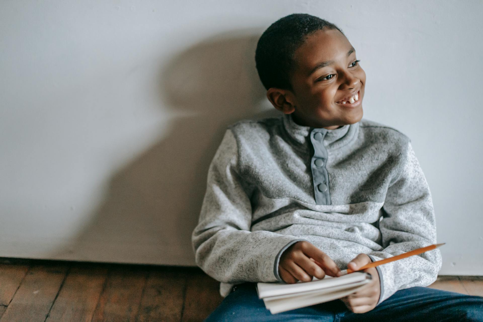 A boy sitting on the floor and laughing | Source: Pexels