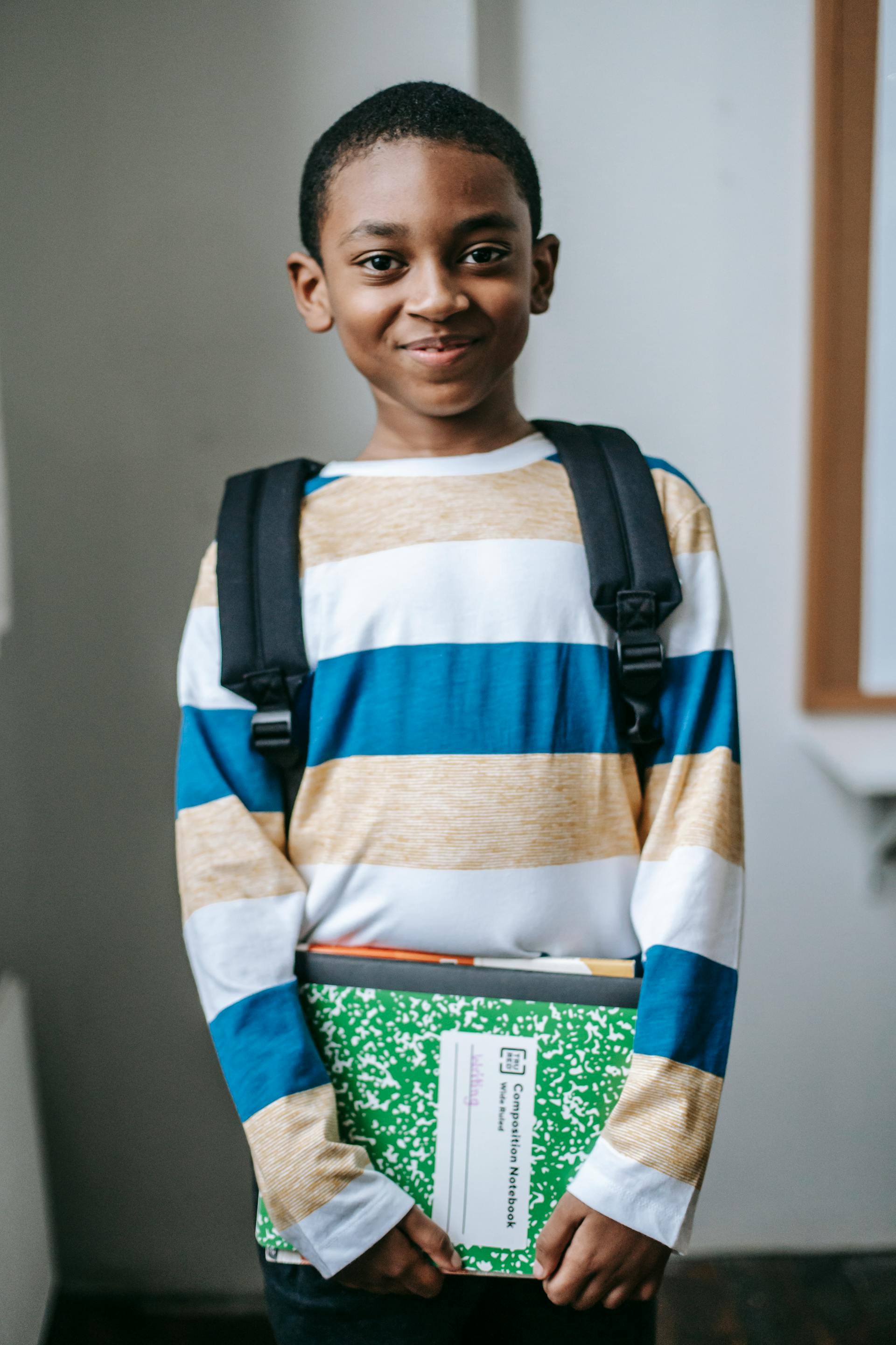 A smiling schoolboy holding books | Source: Pexels