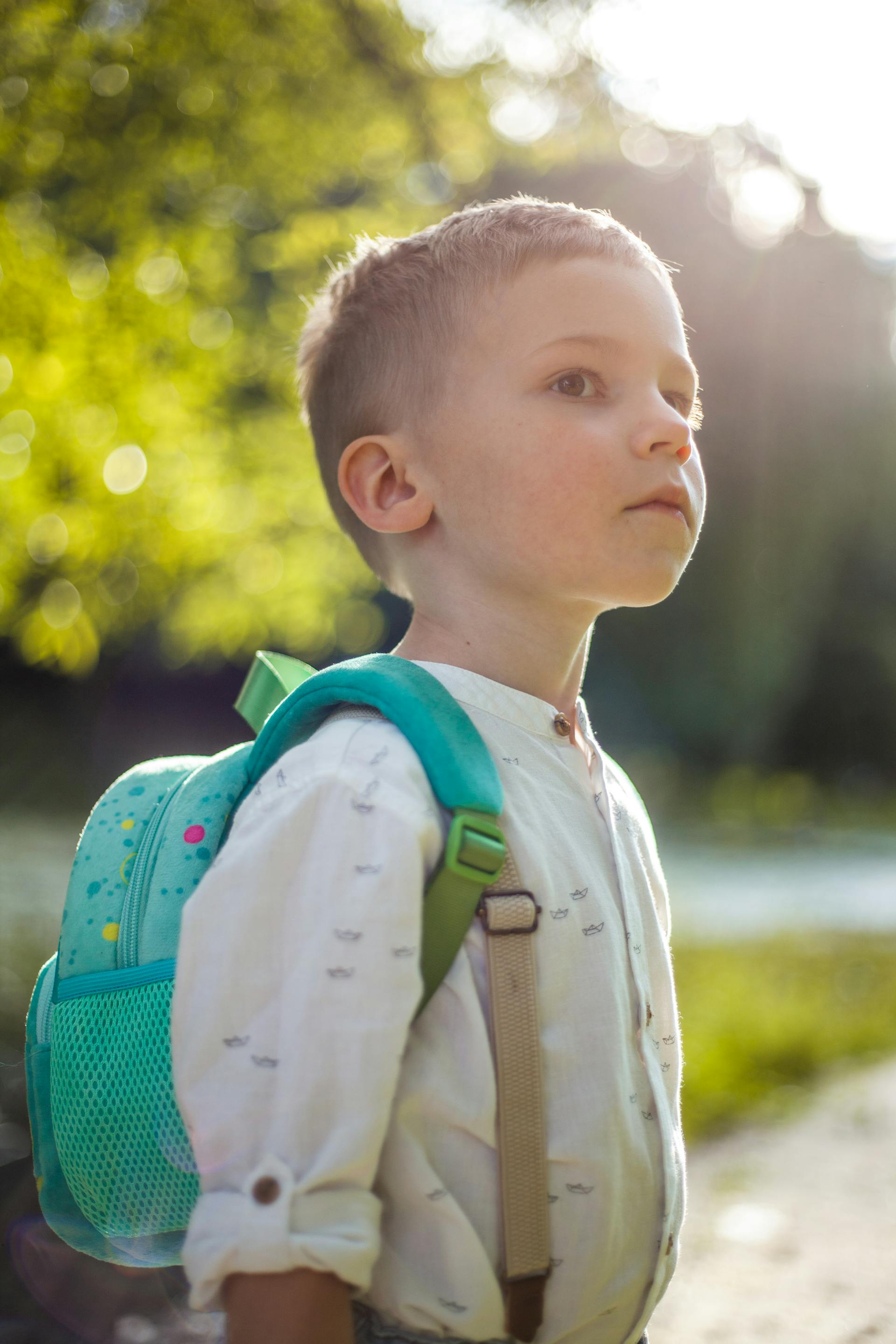 A little boy carrying a blue backpack | Source: Pexels